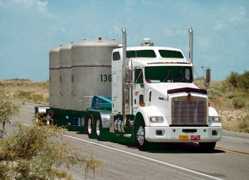 A CAST Transportation truck transporting three TRUPACT-II shipping containers on the highway.