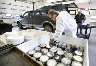 photo - At the El Paso County Household Hazardous Water facility, Chemical Waste Technician Harry Herriges stacks gallons of paint left by Britt Holstun (background) on Tuesday, November 22, 2016. If the paint is still usable, it will be set out on a shelf and given away to whoever gets it first. photo by Jerilee Bennett,The Gazette